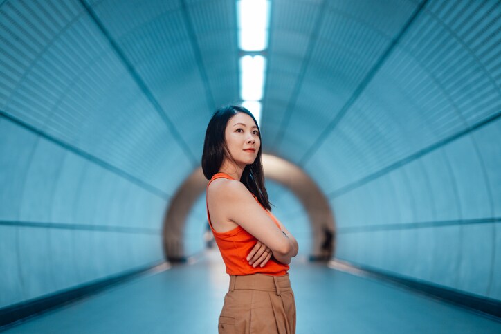 asian woman with arms crossed standing in a futuristic tunnel