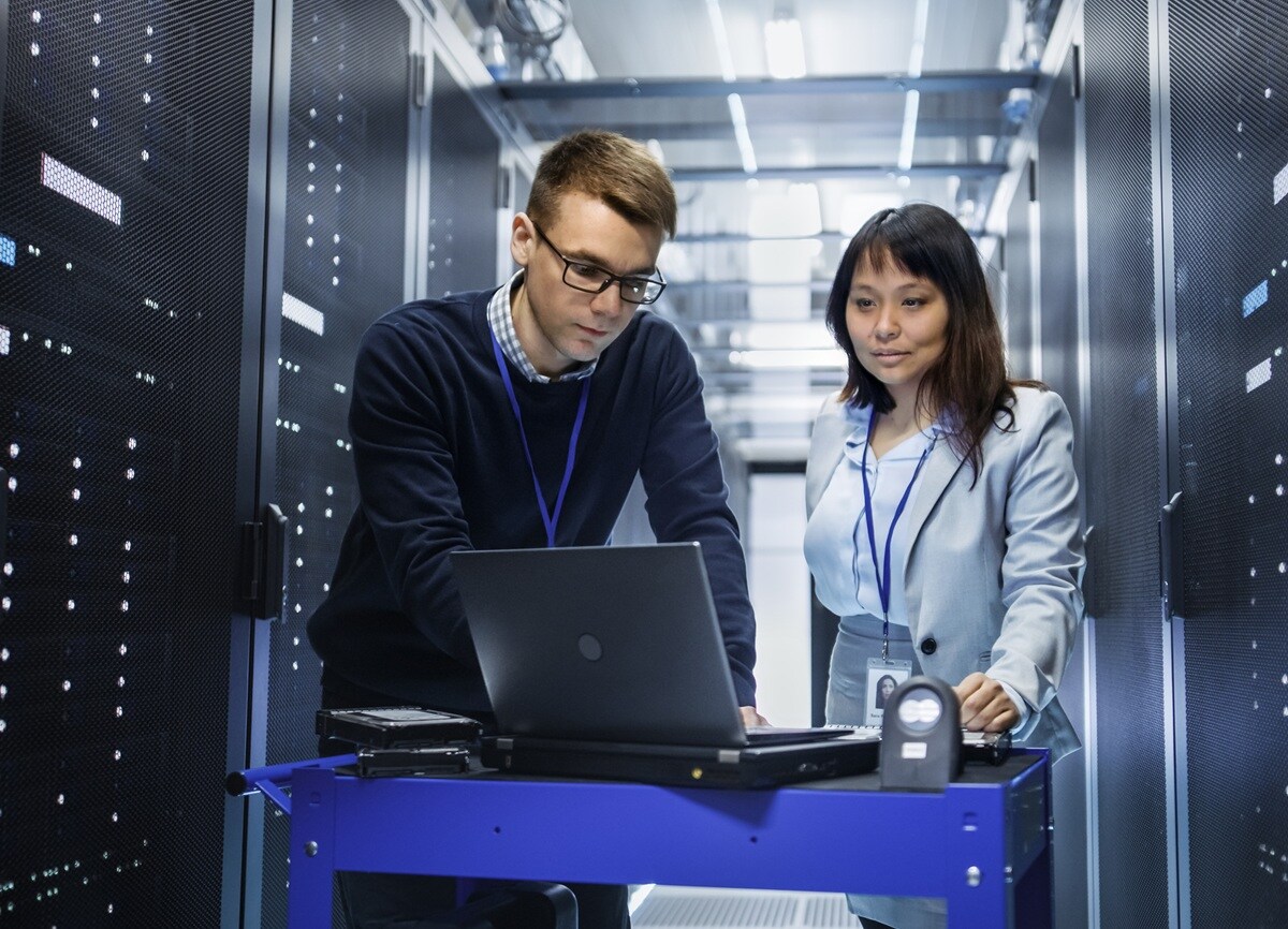 Two people in data centre looking at laptop