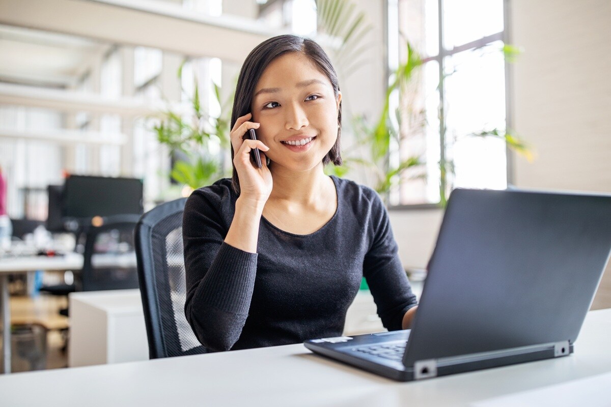 Lady on mobile sitting at desk with laptop open