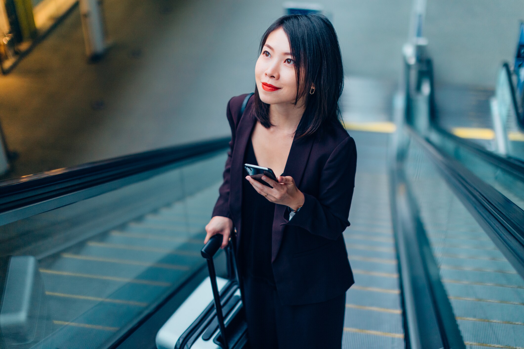 woman with mobile phone travelling on an escalator