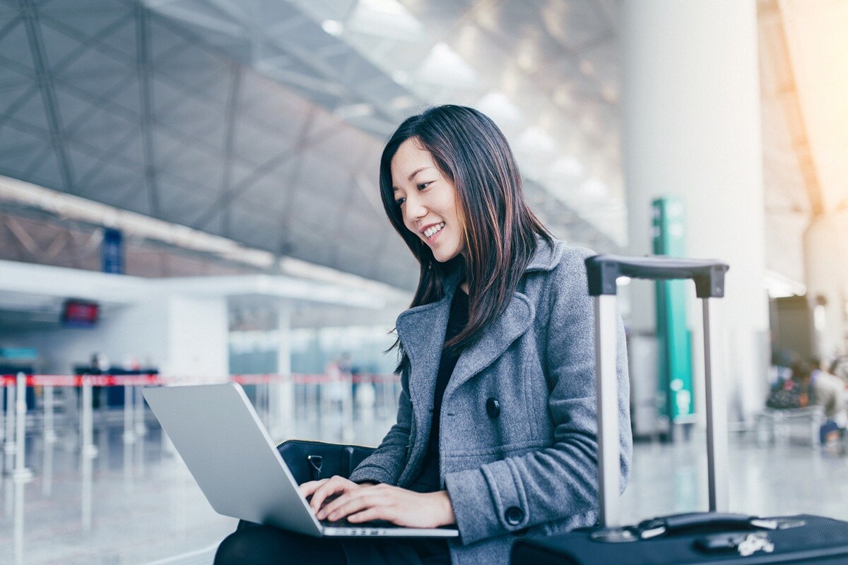 Lady sitting in airport with suitcase next to her