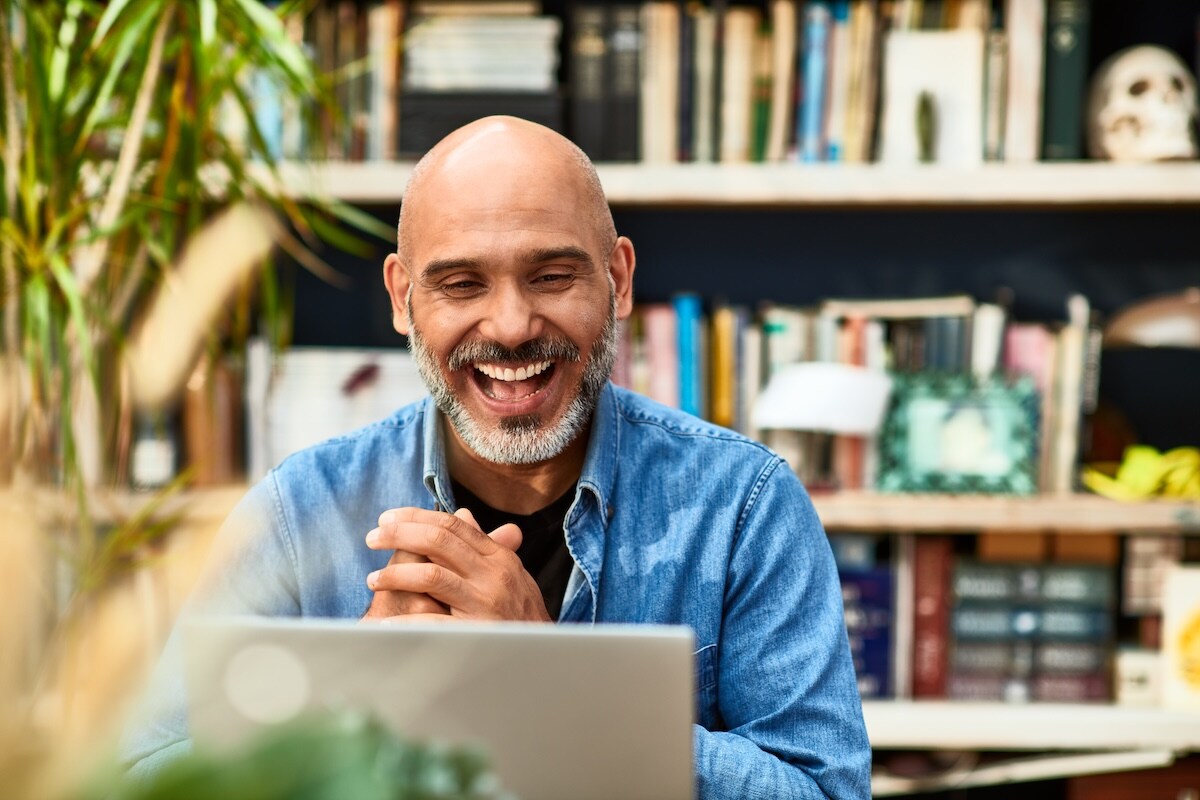 man with beard smiling at laptop 