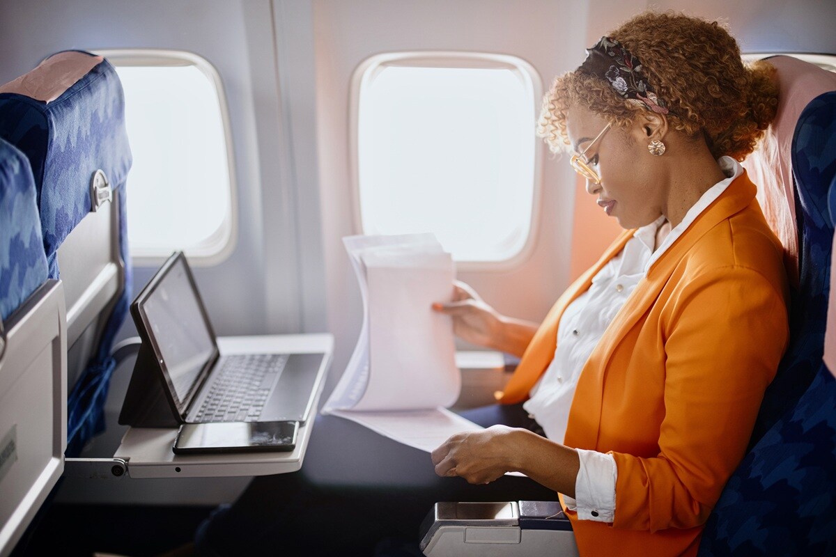 Lady in orange jacket sitting on plane 