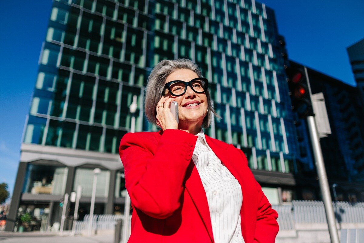 Lady in red jacket standing outside building on her phone