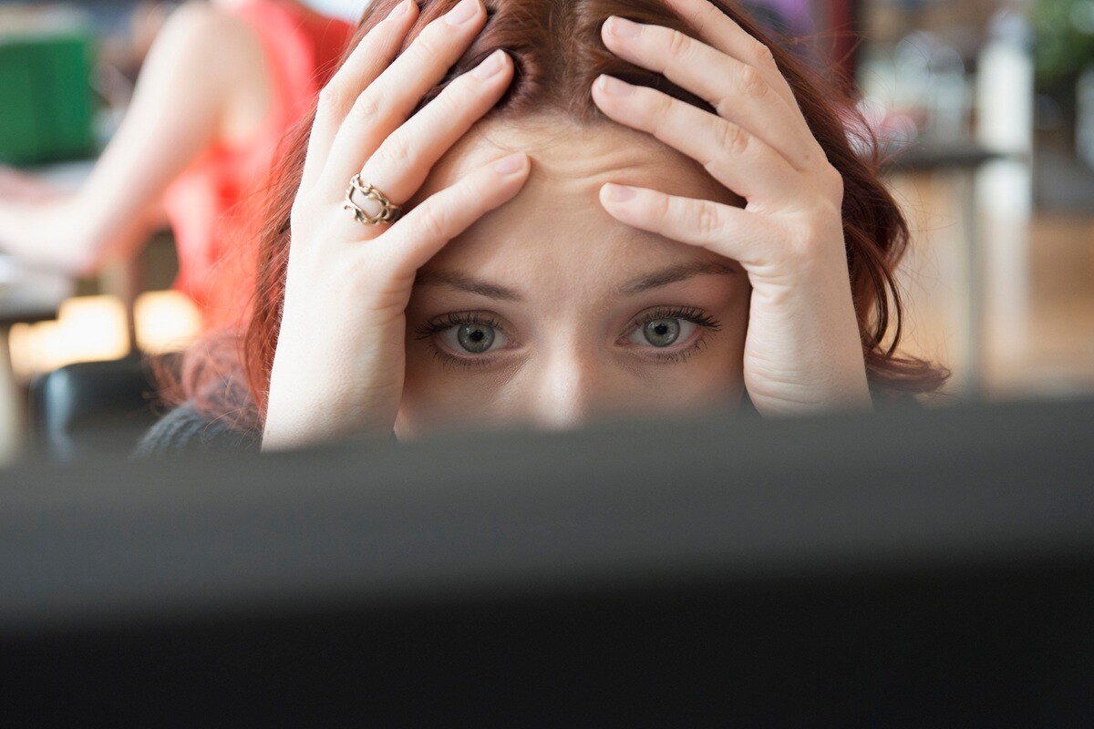 Lady staring at computer screen with head in hands