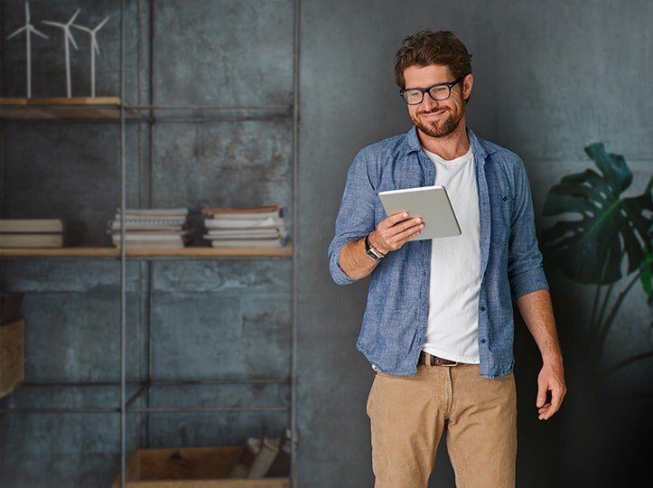 Man standing against a wall looking at tablet