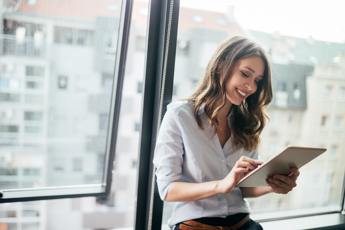 woman smiling while holding a tablet