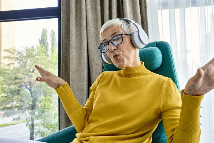Lady in yellow jumper sitting on chair with headphones on