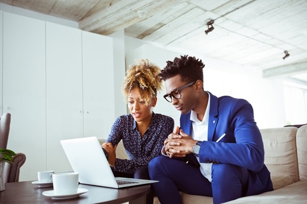 Male and female colleague looking at laptop in white office 