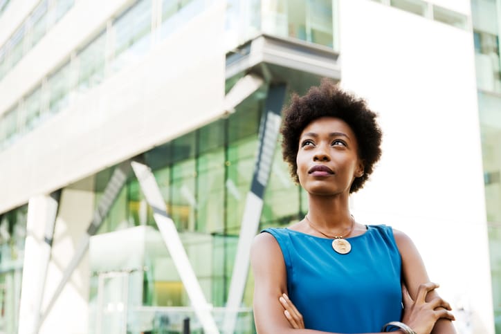 Lady in blue top standing in front of glass building 