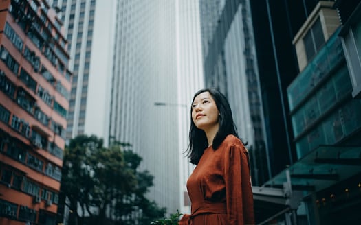 Lady with long black hair in brown dress standing on street outside office