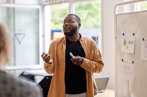 Man standing in front of whiteboard with chart print outs stuck to it