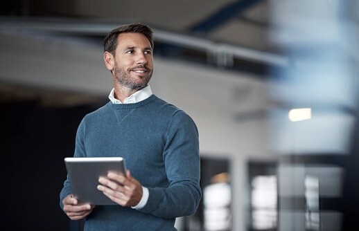 Man in white shirt and blue jumper standing in office 