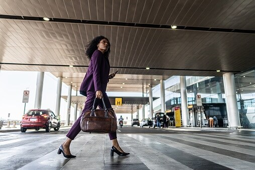 Lady in purple dress crossing road at airport