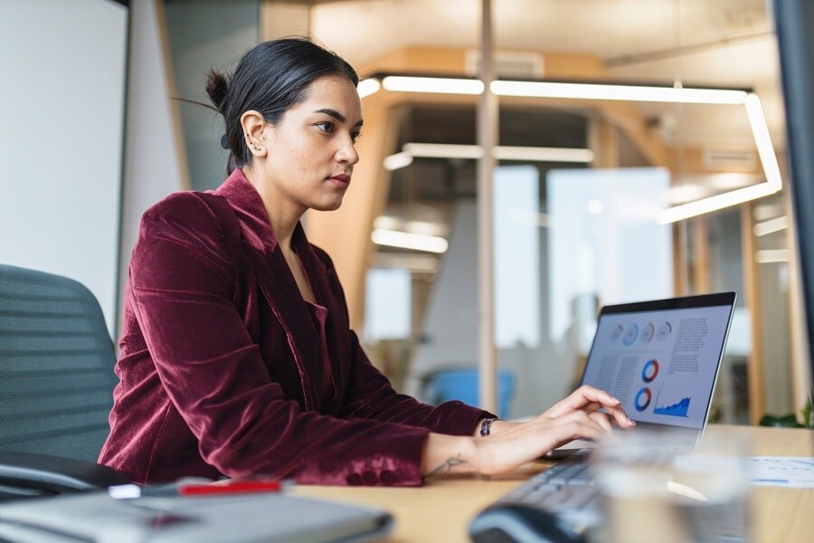 Lady in red velvet jacket sitting at desk with laptop open